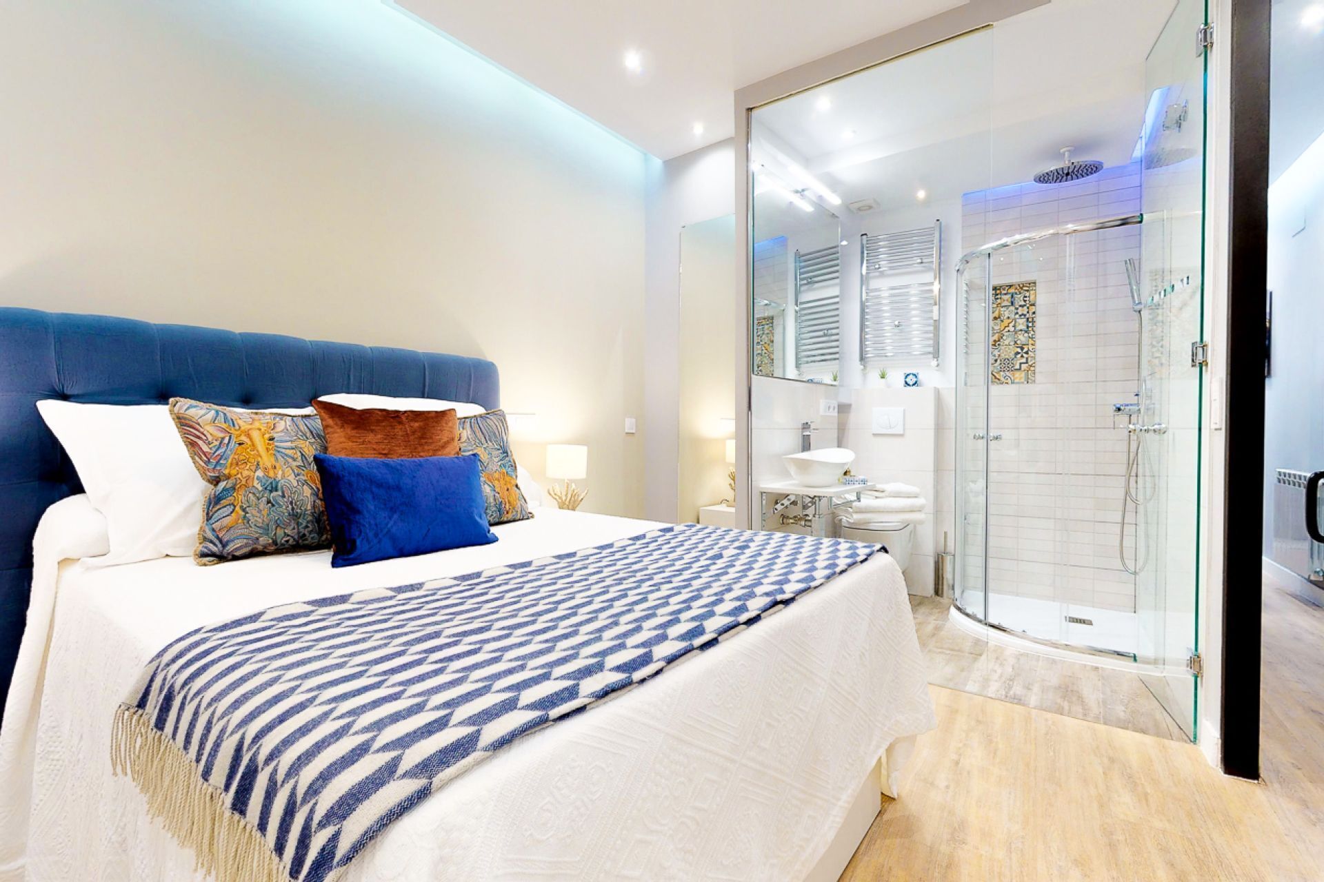 Ein Schlafzimmer mit einem großen Bett, einer Glasdusche und einem weißen Badezimmer.