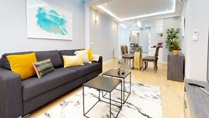 Een moderne woonkamer met een grijze bank, een salontafel en een eethoek met stoelen en een tafel.