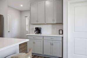A kitchen with white cabinets, a countertop, and a coffee maker.
