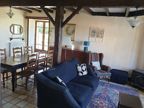 A cozy living room with a sofa, a patterned rug, a dining table with chairs, and a fireplace. - Paradise Francais - your home from home in SWFrance. (Balledent)