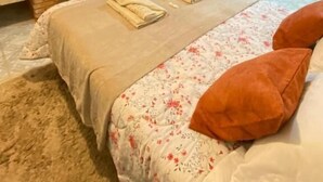 A hotel room with a fireplace, a bed with floral bedding, and a television mounted above the fireplace. - villaggio farnese (Campos do Jordão)