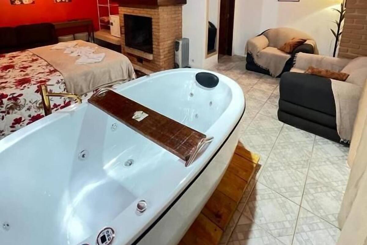 A room with a hot tub, a fireplace, and a sofa.
