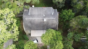 Luchtbeeld van een gebouw met een schuin dak, omgeven door weelderige begroeiing.