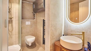 Une salle de bain moderne dotée d’une douche à parois de verre, de toilettes et d’un meuble-lavabo avec un évier et un miroir.
