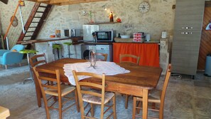 Een landelijke keuken met een houten tafel, stoelen, een magnetron en een spoelbak.
