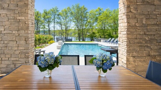 Piscina com vista para árvores e céu azul.