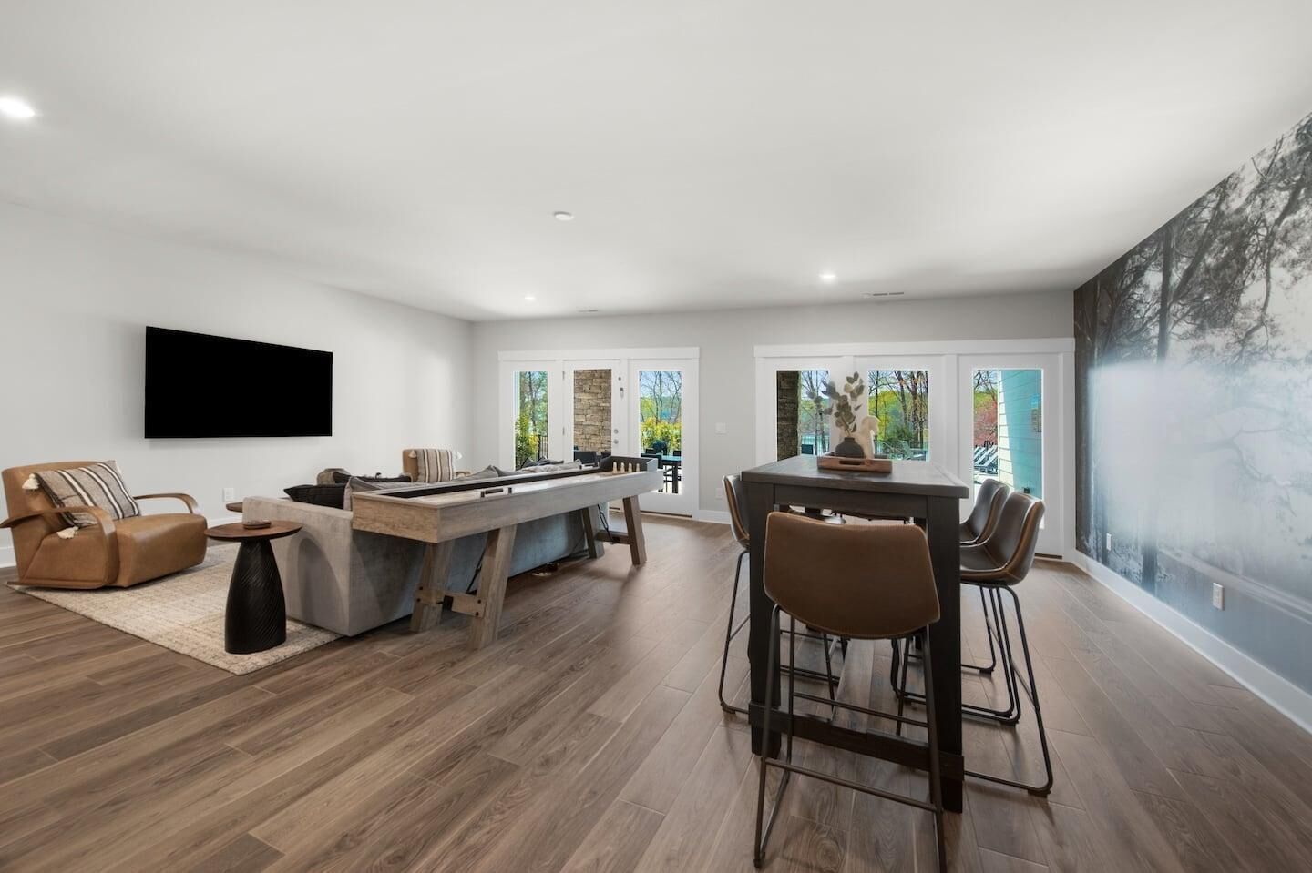 A modern living room with a pool table, a sofa, and a dining area with chairs.