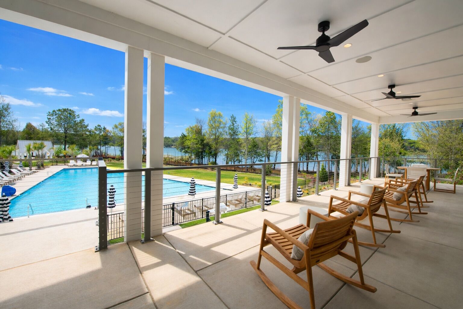 A covered outdoor area with a pool, lounge chairs, and a view of a lake.