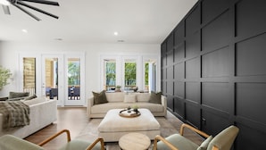 Uma sala de estar moderna com um sofá modular, duas poltronas, uma mesa de centro e uma parede de destaque preta.