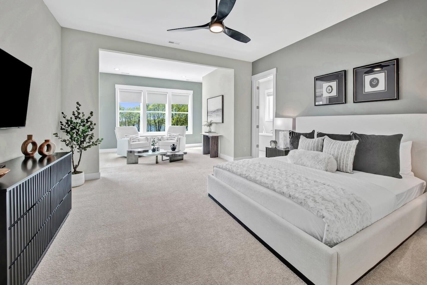 A modern bedroom with a large bed, a ceiling fan, and a view of the outdoors.
