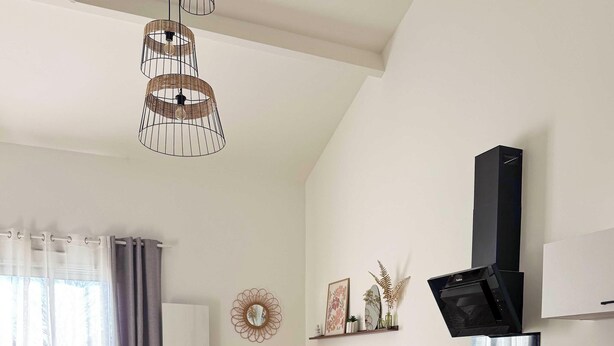 Una cocina moderna con extractor de aire negro, una mesa de comedor con sillas y una sala de estar con sofá y mesa de centro.