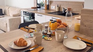 Una cocina moderna con horno empotrado, máquina de café y comedor con productos para el desayuno.