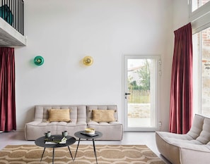 Un salon comprenant un canapé, deux tables d’appoint, une porte donnant sur l’extérieur et un balcon avec une balustrade.