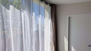 A room with a window featuring sheer curtains and a view of trees. - Tranquiloue - Appart 4 pers - Puy du Fou 17 min (Chanverrie)
