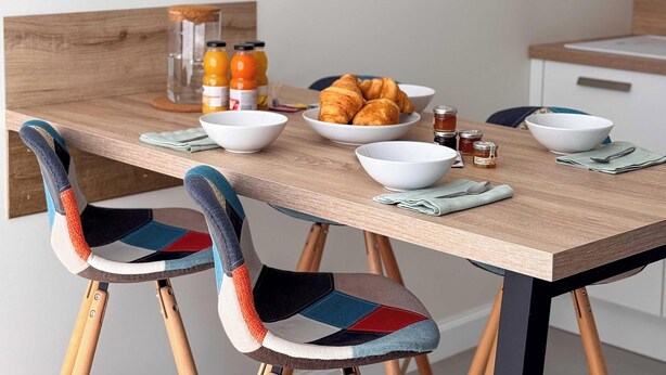 A dining table with chairs, a clock, and breakfast items. - Tranquiloue - Appart 4 pers - Puy du Fou 17 min (Chanverrie)