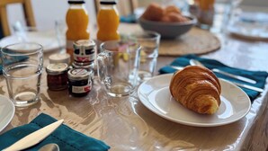 Ein Frühstückstisch mit einem Croissant, Gläsern und Beilagen.