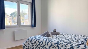 Ein Schlafzimmer mit Bett, Fenster, Heizkörper und einer Pendelleuchte.