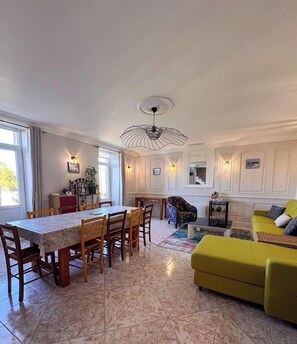 Un coin repas comprenant une table et des chaises, un canapé et un luminaire décoratif au plafond.