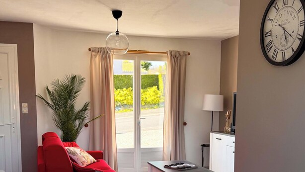Una habitación con una mesa de comedor, un sofá rojo y un reloj en la pared.