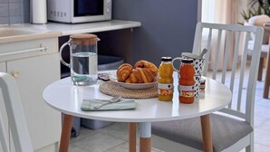 Una cocina con microondas, una mesa con croissants, una jarra de agua y dos botellas de jugo.