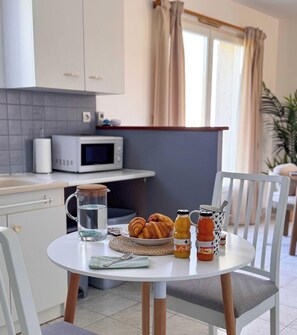 A kitchen with a microwave, a table with croissants, a pitcher of water, and two bottles of juice. - Tranquiloue - Maison 6 pers - 15 min du Puy du Fou (Sèvremont)