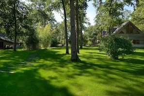 Une maison entourée d’arbres, avec une pelouse et un chalet en bois.