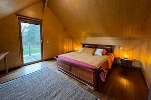 A wooden room with a bed, a table, and a lamp. - L'Atelier, cosy and modern & terrace with jacuzzi (Rives-du-Loir-en-Anjou)