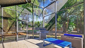 Un patio techado con una parrilla, una mesa y un equipo de aire acondicionado grande.