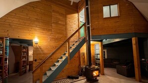 Um interior de madeira com escada, lareira e sala de estar.