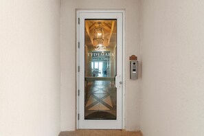 A door with a glass panel, a sign reading 'TYDEMARK CLUB ROOM FITNESS ROOM,' and a control panel to the right. - Tydemark 502 (New Smyrna Beach)