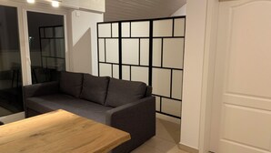A modern living room with a grey sofa, a wooden table, and a white door. - Delightful 1-bedroom apartment in Safenwil perfect for your stay (Safenwil)