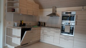 A modern kitchen with built-in appliances, wooden cabinetry, and a stainless steel range hood. - Delightful 1-bedroom apartment in Safenwil perfect for your stay (Safenwil)