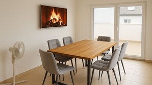 A dining area with a wooden table and six chairs, a wall-mounted TV, and a sliding glass door to the outside. - Delightful 1-bedroom apartment in Safenwil perfect for your stay (Safenwil)