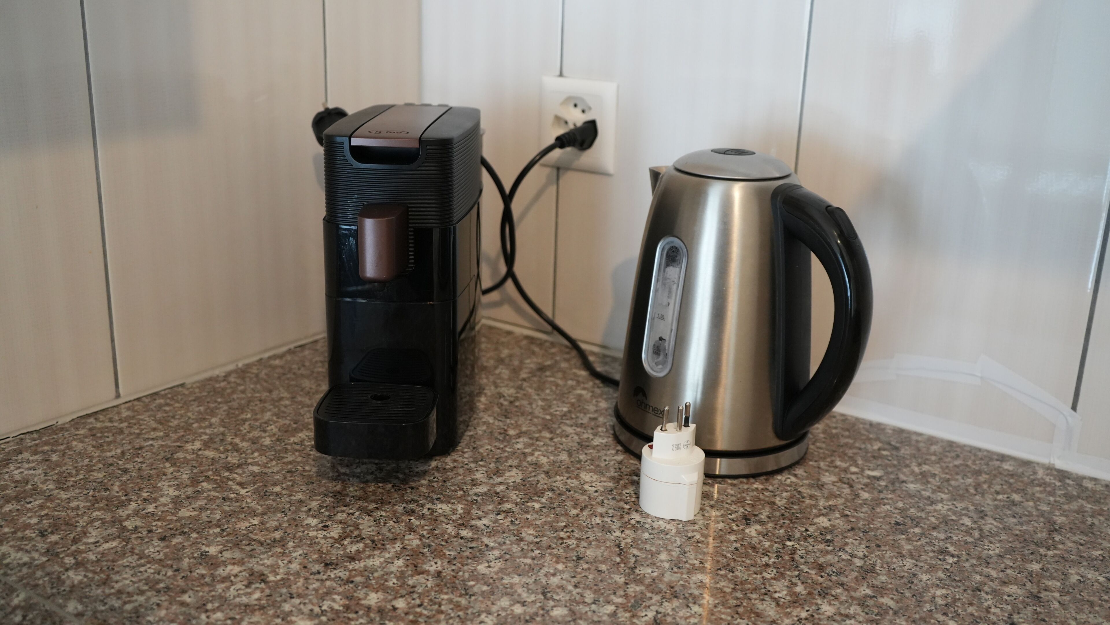 Eine Kaffeemaschine und ein Wasserkocher auf einer Granit-Arbeitsplatte.