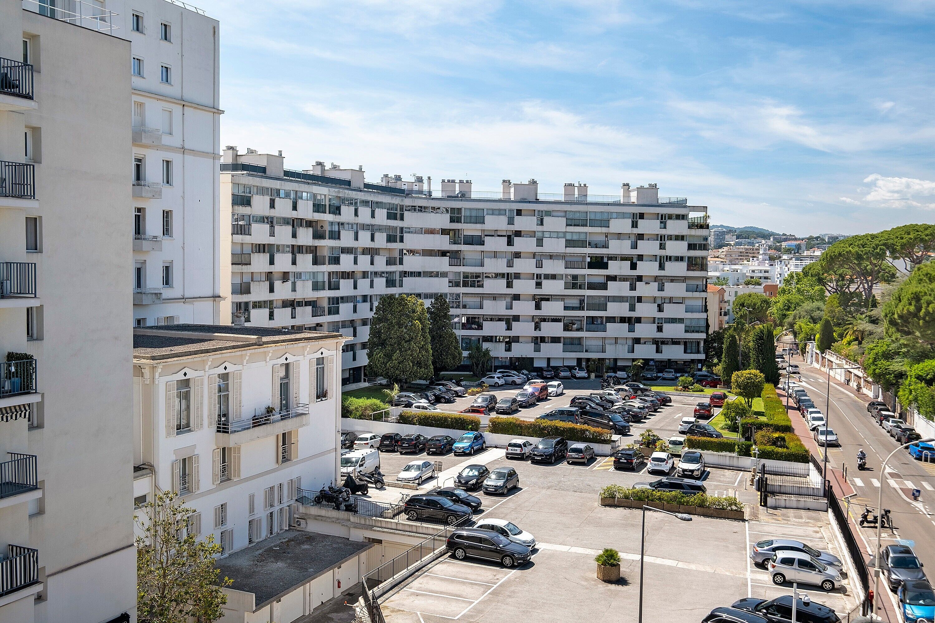 Un parking à étages où sont garées plusieurs voitures, entouré d’immeubles dotés de balcons et de fenêtres.