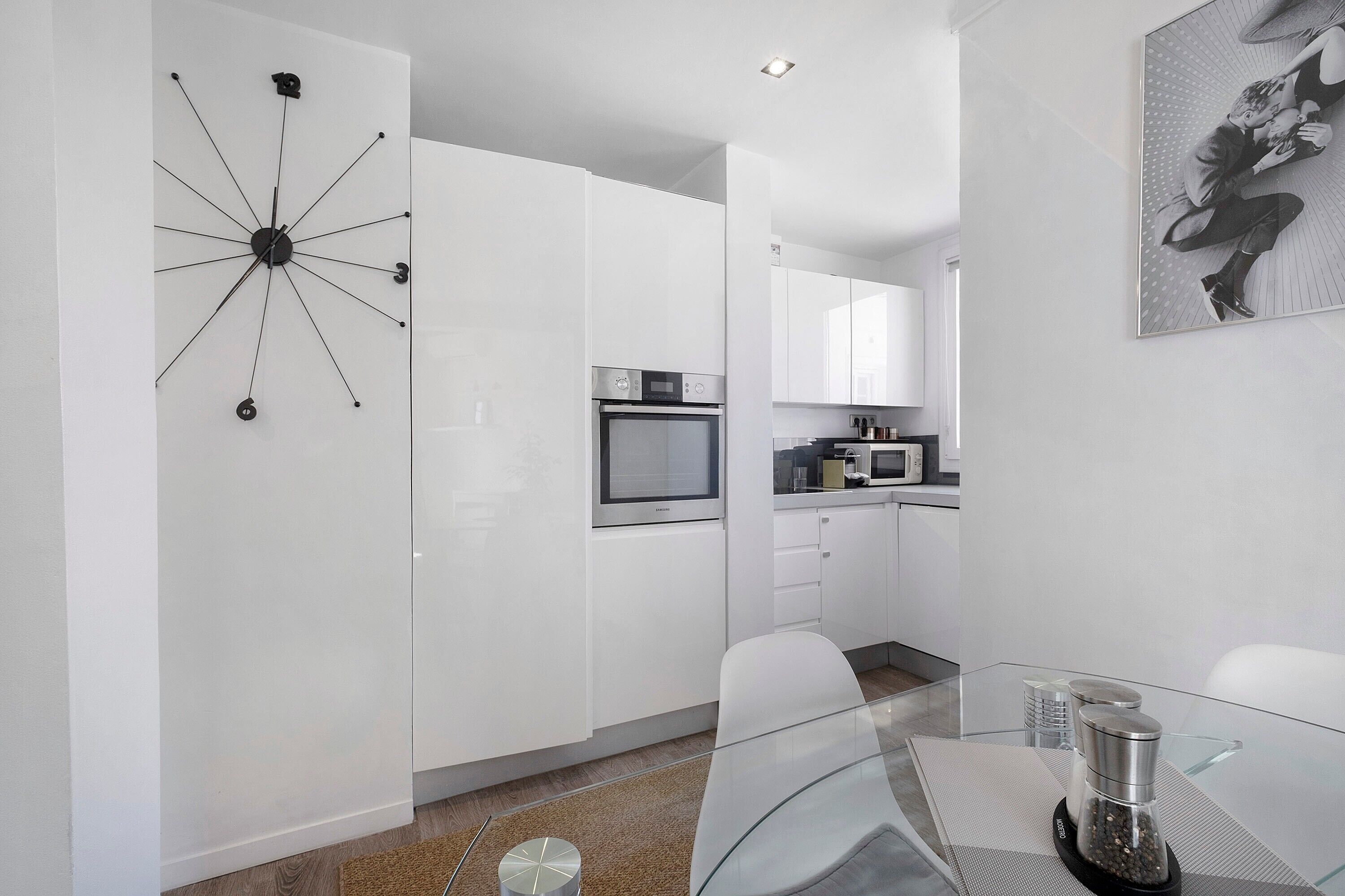 A modern kitchen with white cabinets, a built-in oven, and a microwave.