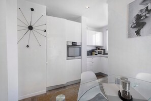 Une cuisine moderne avec des meubles blancs, un four encastré et un four à micro-ondes.