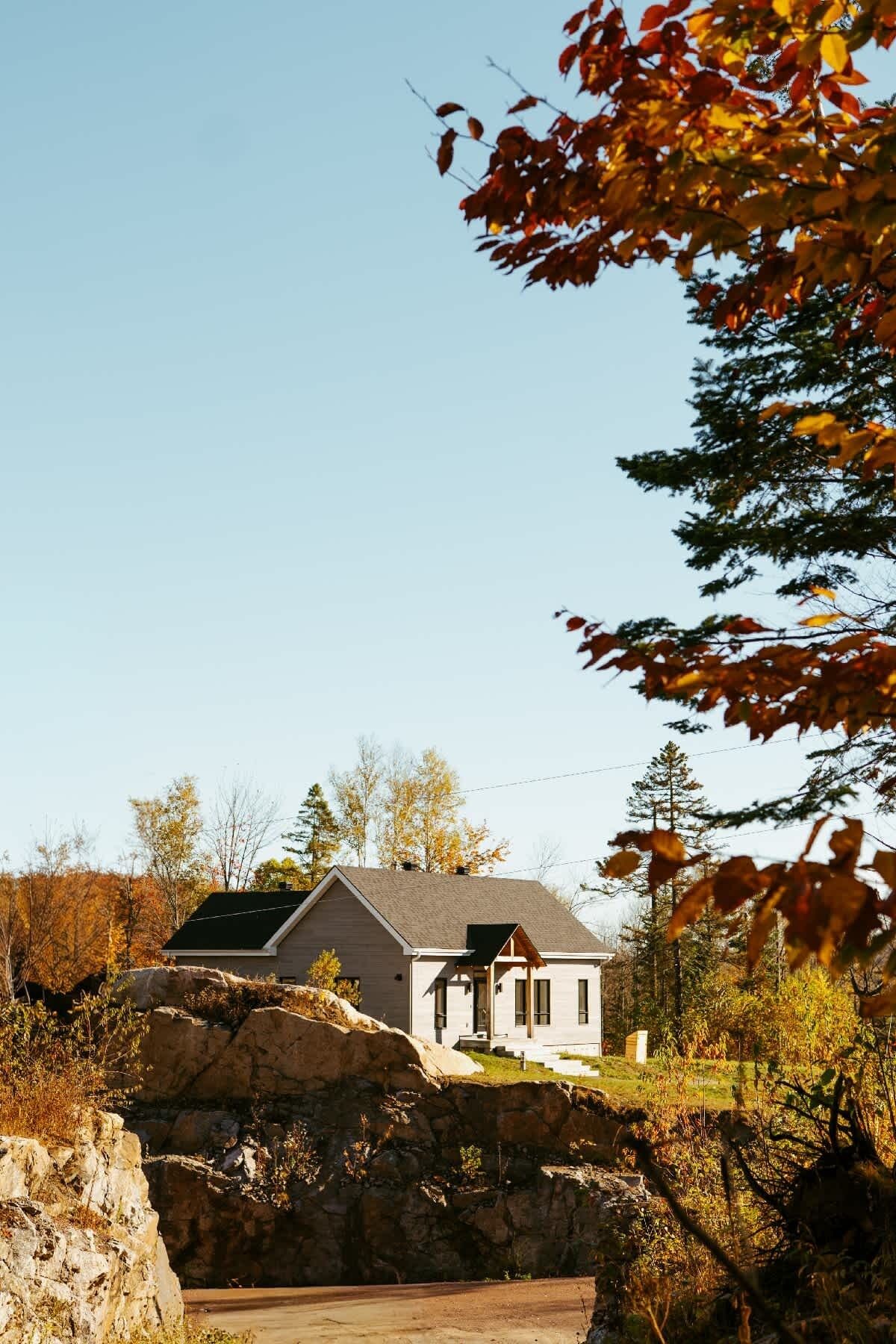 A modern house with a sloped roof, a stone retaining wall, and a clear sky.