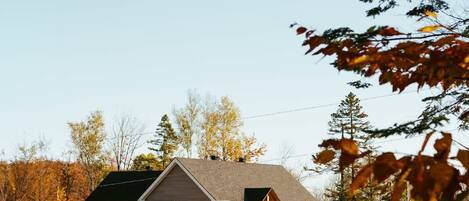 A modern house with a sloped roof, a stone retaining wall, and a clear sky.