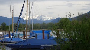 A marina with boats covered by blue tarps, a mountain range in the background, and a clear sky.