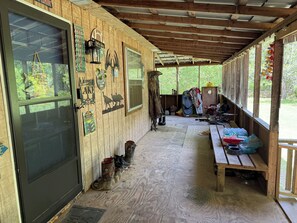 A covered wooden structure with a door, windows, and various signs.