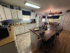 A kitchen with white cabinets, a wooden countertop, and a central island with stools.
