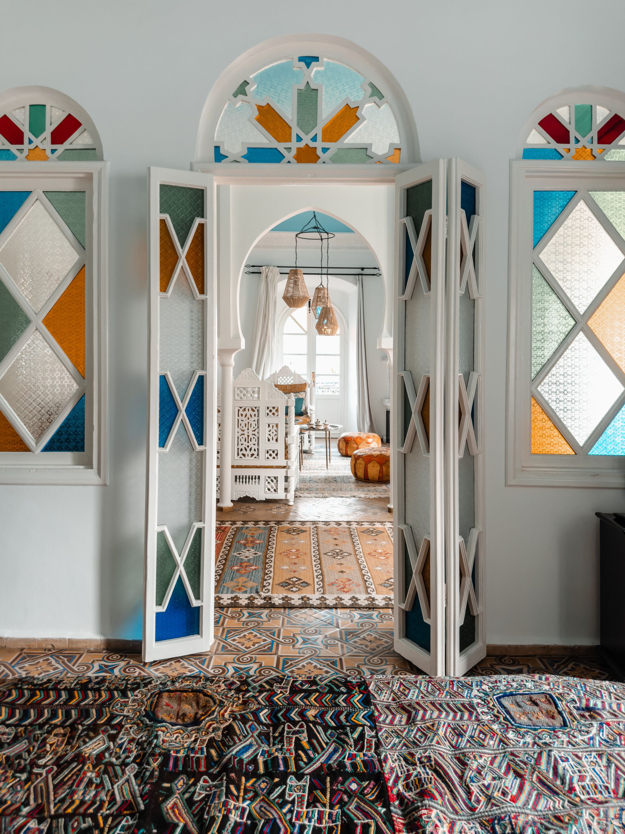 A room with a patterned carpet, a white door with geometric glass panels, and a hanging light fixture.