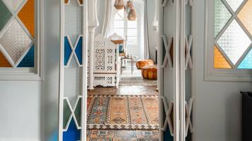 A room with a patterned carpet, a white door with geometric glass panels, and a hanging light fixture.