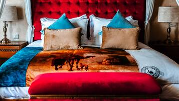 Una cama con cabecera roja, varios cojines y una manta colorida.