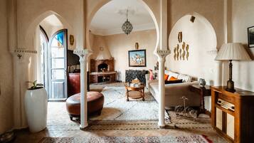 A spacious living room with a fireplace, a sofa, a coffee table, and a patterned rug.