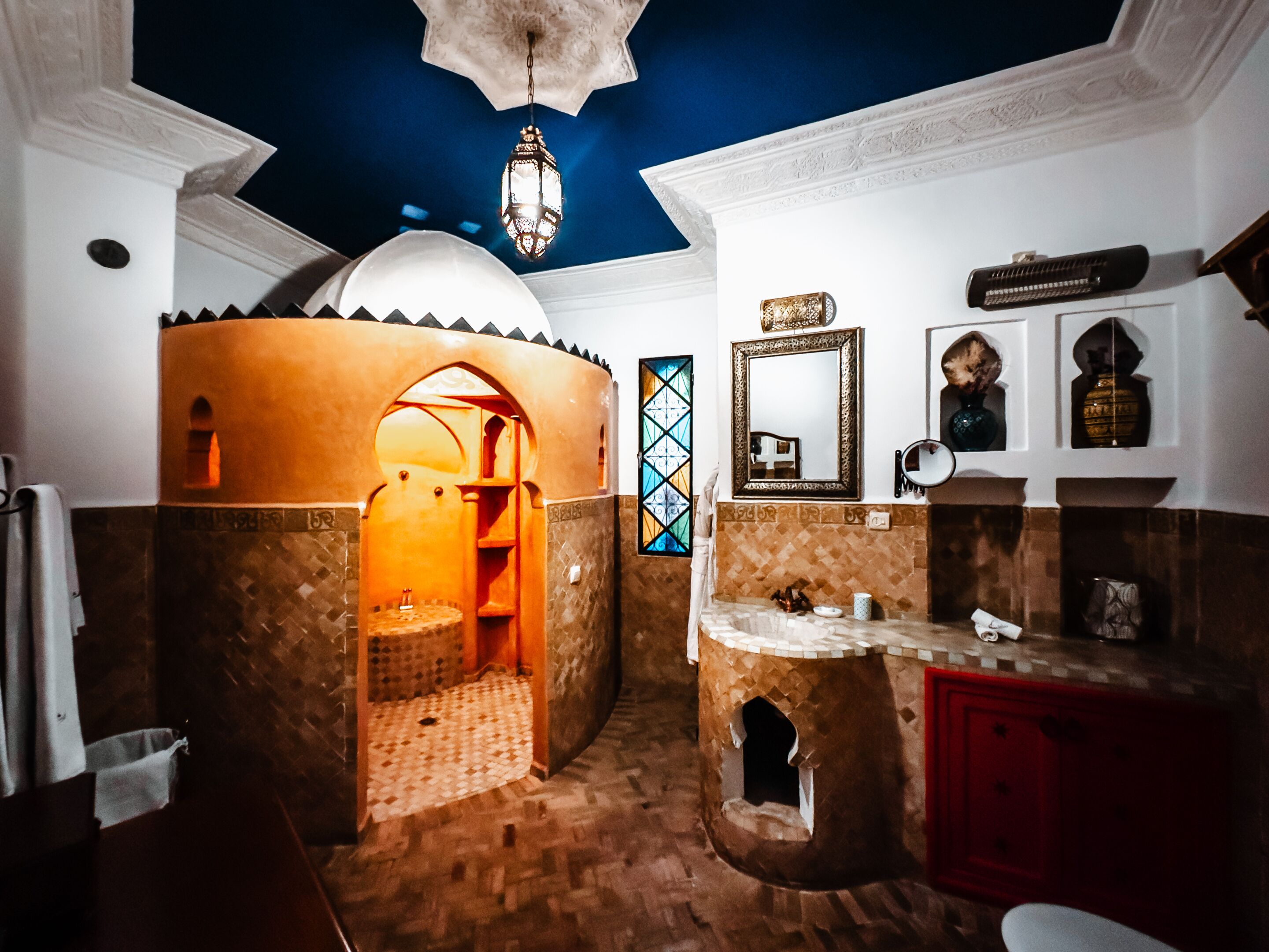 Un baño con un diseño arquitectónico único, que incluye una pequeña estructura tipo torre, un espejo y un farol decorativo.