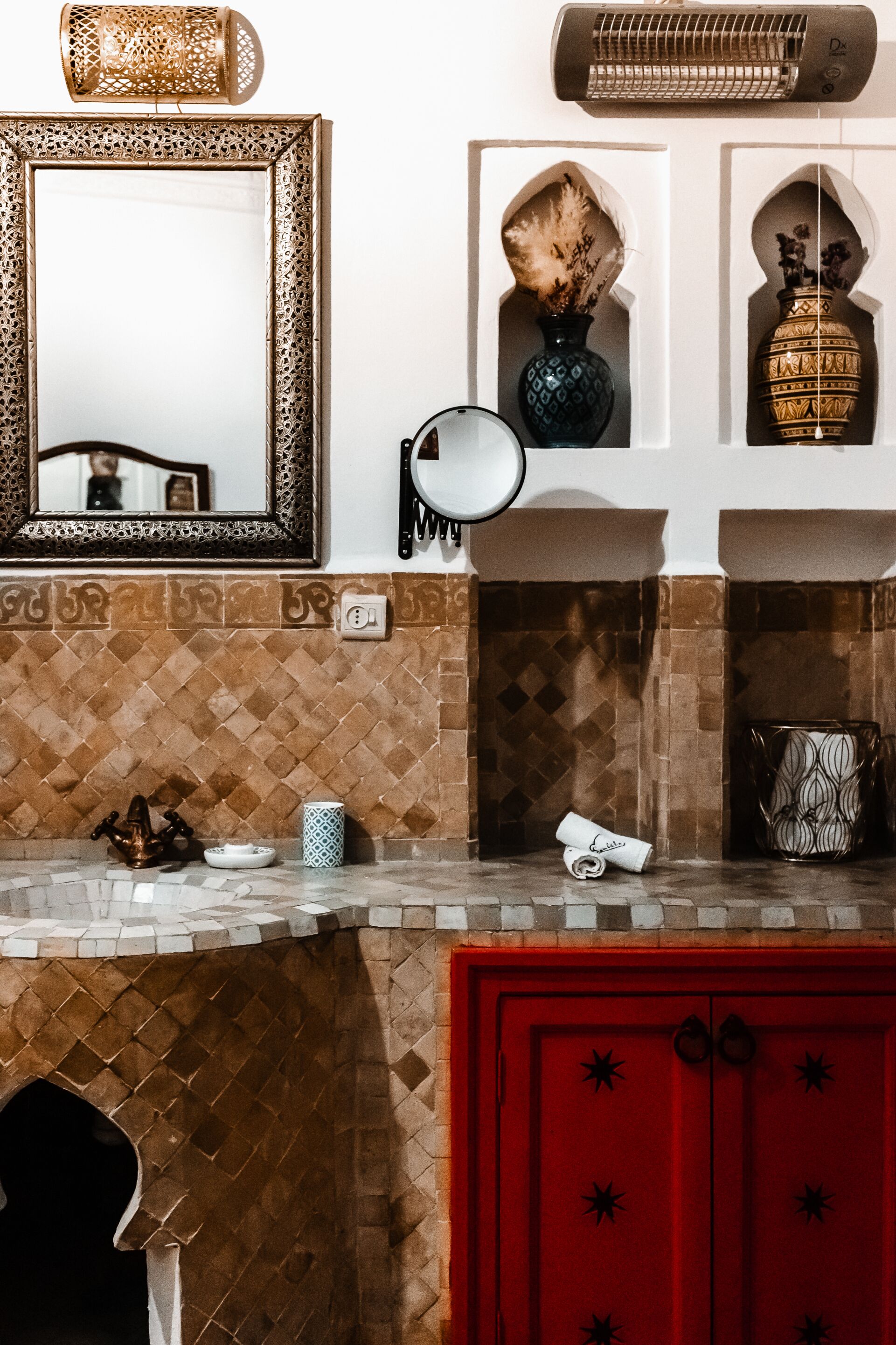 A bathroom with a mirror, a towel, a sink, and a red cabinet.