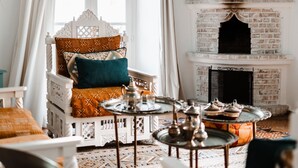 A room with a white arched window, a white fireplace, and a patterned rug. - Lalla Soulika (Tangier)