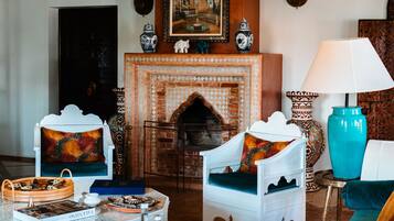 A room with a fireplace, white furniture, a chandelier, and a patterned rug.